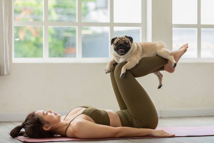 7 Powerful Spiritual Practices to Overcome Anxiety and Fear - woman practicing yoga with little dog resting on her legs.