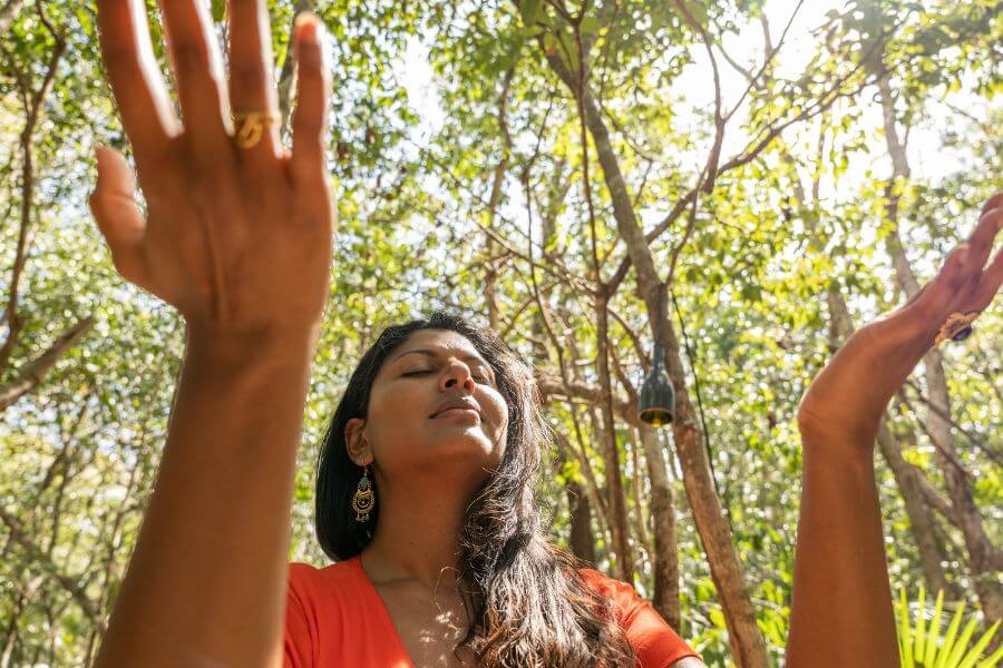 7 Powerful Spiritual Practices to Overcome Anxiety and Fear - Woman in nature lifting her hands up in front of her to feel the spiritual vibrations.