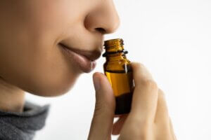 The Power of Essential Oils How to Overcome Depression - woman gently sniffing an essential oil in a small dark brown glass bottle.